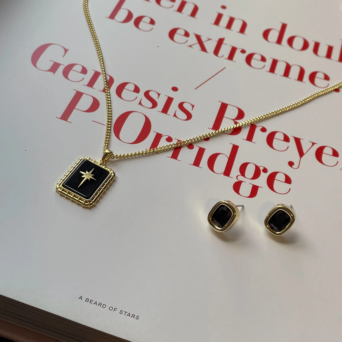 Black and gold pendant necklace and earrings on an open book